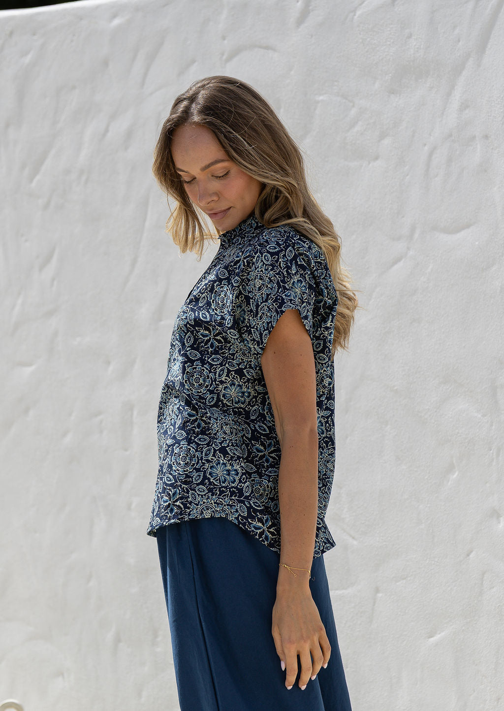 Woman wearing a floral cotton top with short folded cuff sleeves, collar and V neckline