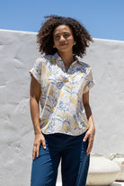 Woman poses in relaxed fit cotton short sleeve top with rolled cuffs sleeves, collar and V neckline.