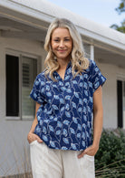 Woman poses in relaxed fit cotton short sleeve top with rolled cuffs sleeves, collar and V neckline.