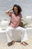 Woman sitting outdoors wearing 100% cotton top with white pants 