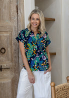 Woman wearing a navy blue based relaxed fit, shirt style floral cotton top with plain pants.