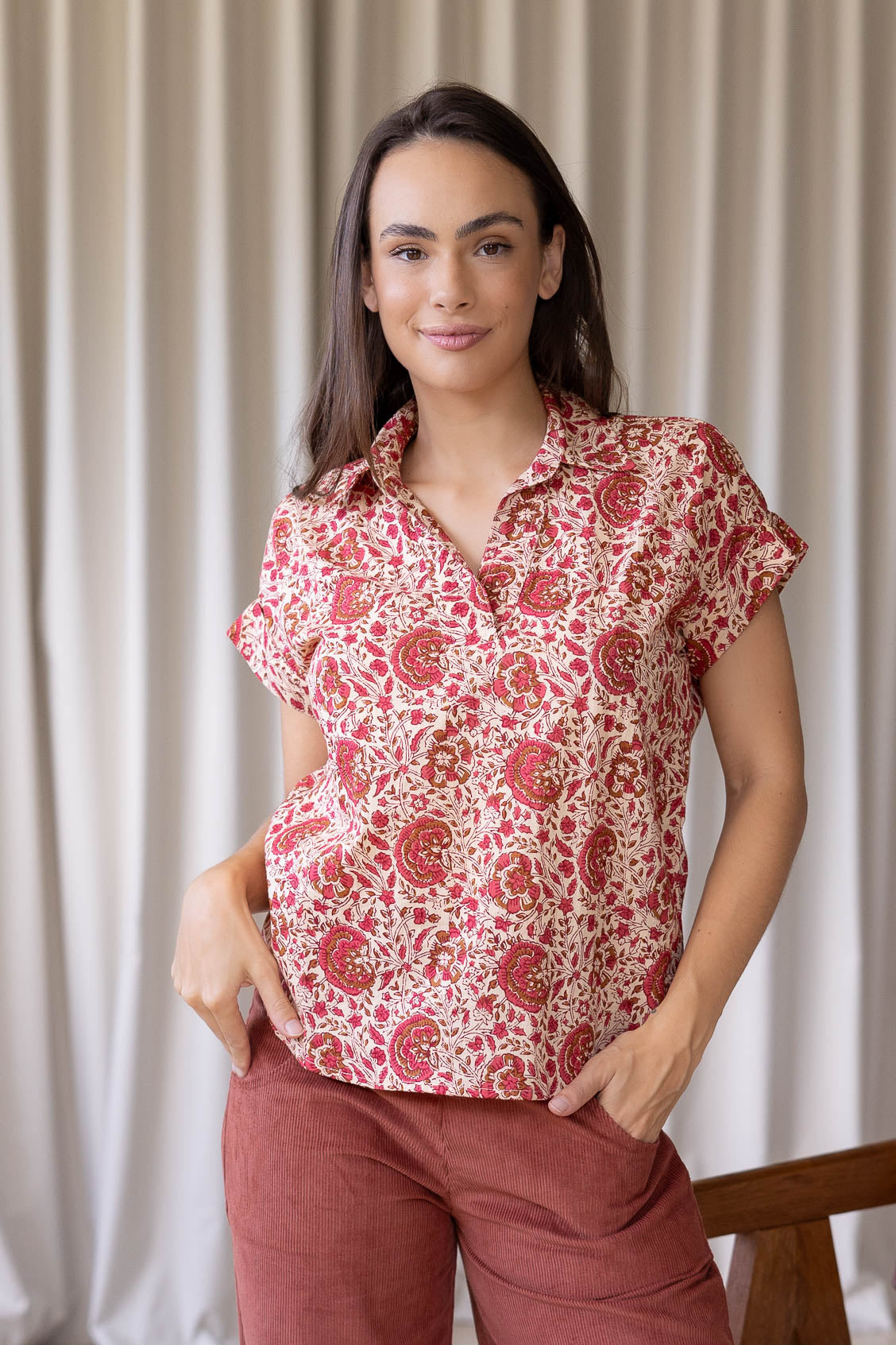 Woman poses in relaxed fit cotton short sleeve top with rolled cuffs sleeves, collar and V neckline.