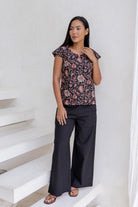 Model wears black cotton pants and dark floral cotton top with tailored fit, cap sleeves and round neckline.