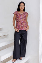 Woman wearing a floral cap sleeve top  blending pink, maroon, brown, peach and khaki palette.