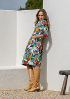 Woman standing sideways wearing a knee length sundress with colourful floral print