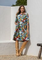 Woman in cotton, floral, knee length sundress with sleeves and hand in pockets