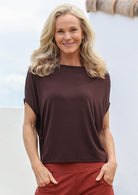 Woman wearing a brown top and red pants with a blurred background