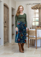 Woman wearing a cotton velvet skirt in teal based multi-coloured floral print with a basic top. 