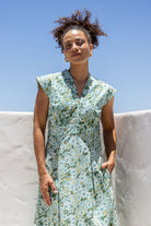 Woman wearing a retro style cotton dress with side zipper, cap sleeves and A line skirt in sage green based floral print