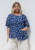 Woman wears 100% cotton relaxed fit top in navy based floral print with an asymmetrical hem line.
