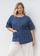 Woman wears a navy and white striped 100% cotton relaxed fit top with an asymmetrical hem line.