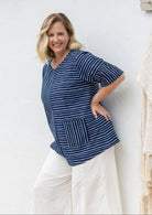 Woman wears a navy and white striped 100% cotton relaxed fit top with short sleeves and front pockets