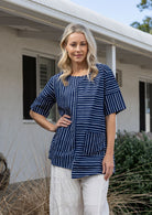 Woman wears a navy and white striped 100% cotton relaxed fit top with short sleeves and front pockets