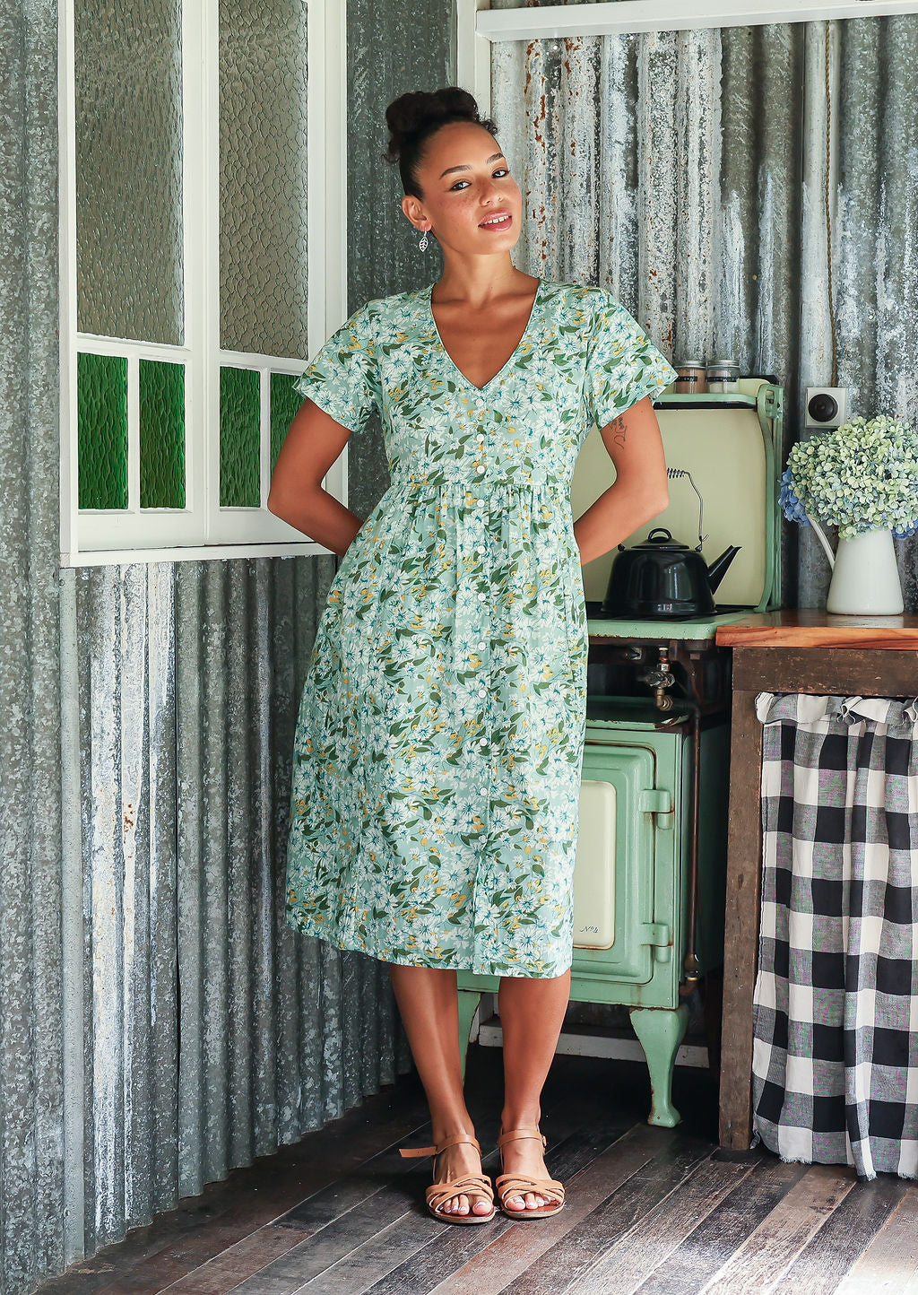 Woman in a cotton mint green based floral button through dress with short sleeves and a V-neckline
