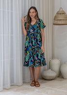 Woman in a cotton navy based floral button through dress with short sleeves and a V-neckline