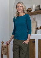 Woman wearing a rayon boat neck teal 3/4 sleeve top.