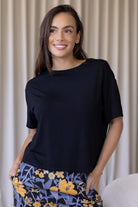 Woman wearing a black relaxed fit stretch rayon top with short sleeves and high round neckline