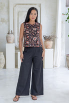 Model stands in black cotton pants and relaxed fit floral print top with round neckline, sleeveless design and side bust darts.