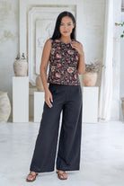 Model wears 100% cotton sleeveless floral  print top in black paired with black wide-leg cotton pants.