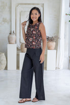 Woman poses in sleeveless, relaxed fit boxy top with high round neckline, and side bust darts in indian floral print on a dark base.