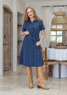 Woman standing in printed shirt dress with detachable fabric belt, short sleeves and pockets.