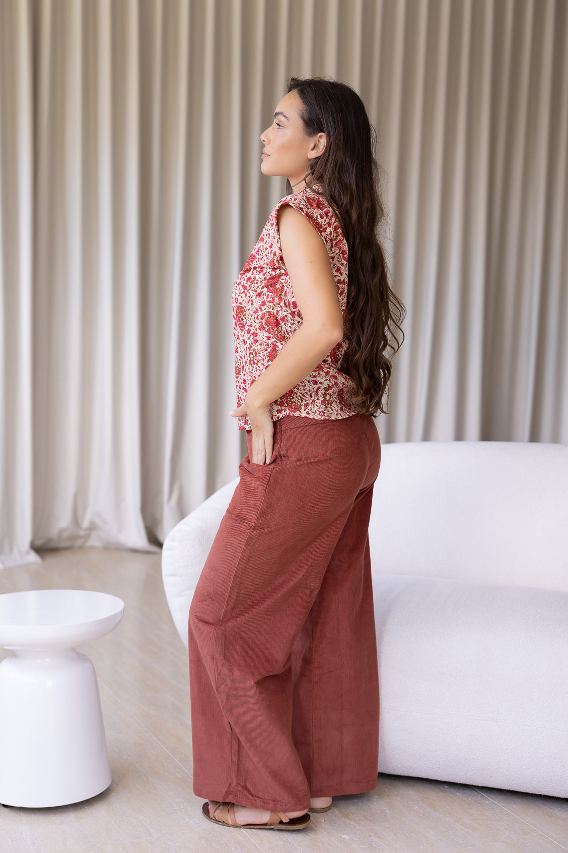 Woman standing sideways wearing slim fit cotton shirt in gentle cream based floral print with plain pants