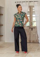 Model standing, wearing a 100% lightweight cotton button up shirt with folded cuff sleeves and collar