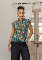 Woman wearing a slim fit button up shirt with shell buttons, structured collar and folded cuff sleeves