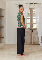 Woman standing sideways wearing a floral printed slim fit cotton shirt with plain black pants in a minimalistic room.