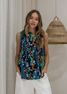 Woman wearing a 100% cotton navy based floral sleeveless top with small pleated design, and buttoned mandarin collar.