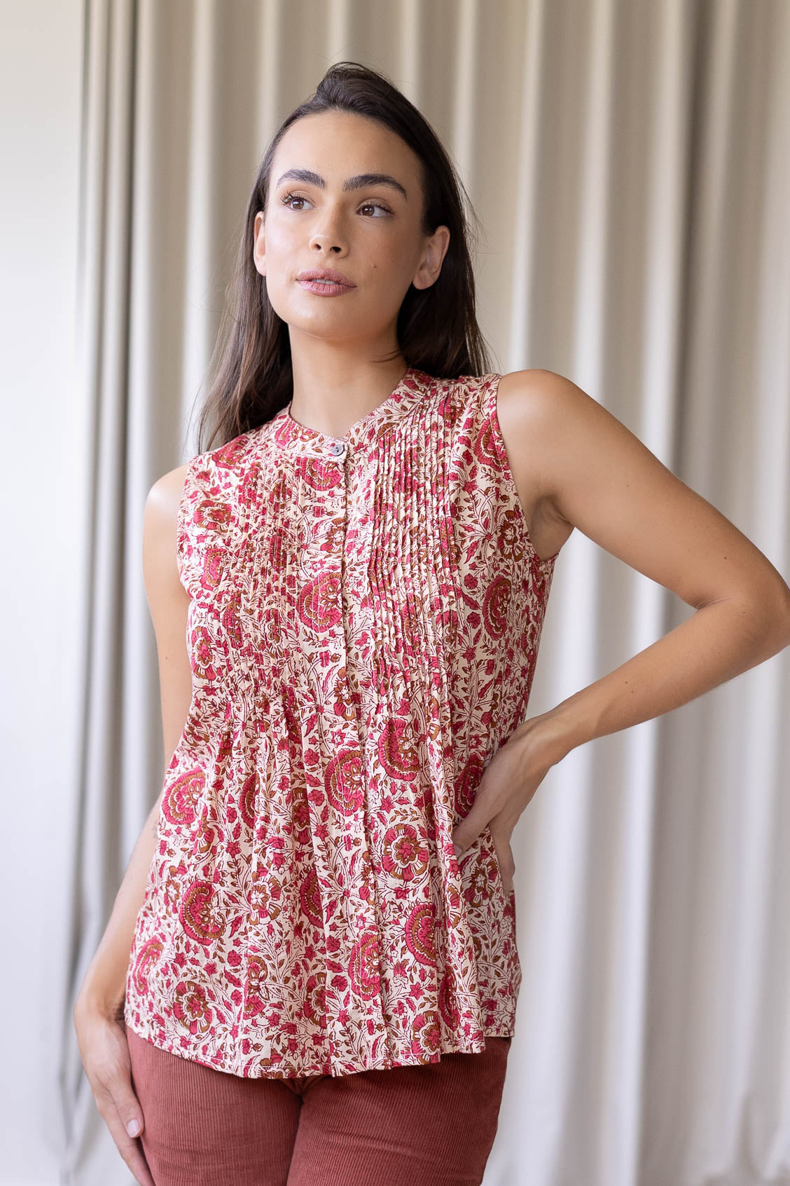 Woman wearing a 100% cotton gentle cream based floral sleeveless top with small pleated design, and buttoned mandarin collar.