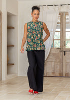 Woman wearing a 100% cotton green based floral sleeveless top with small pleated design, and buttoned mandarin collar.