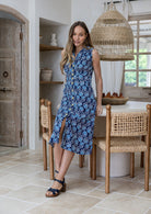 Woman wearing midi length, sleeveless  cotton dress with collar and pockets in navy based floral print.