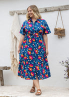 Woman wearing 100 percent cotton button through shirt dress with collar and short sleeves, in a royal blue based floral print. 