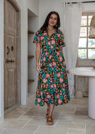 Model poses wearing a shirt style button through cotton dress with collar and a removable waist tie.