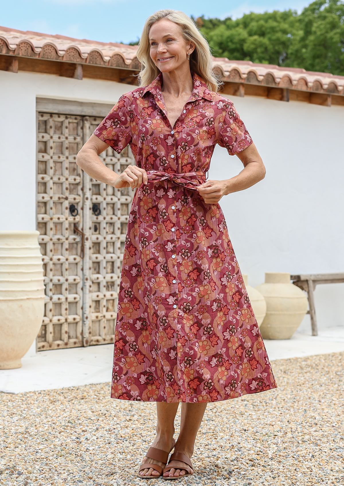 Woman wearing a midi length shirt style  cotton dress with short sleeves, button through front and a detachable fabric waist tie in japanese style warm floral print.