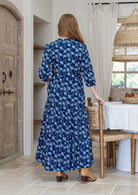 Woman standing backwards wearing a 100% cotton tiered maxi dress in floral print with 3/4 sleeves, pockets and mandarin collar