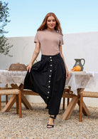 Woman wearing a belt loop and box pleat detailed midi length A-line black cotton skirt