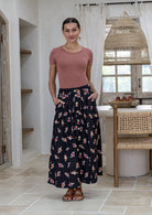 Woman standing with both hand in pockets wears 100% cotton button through skirt in black based floral print. 
