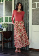 Woman wearing a pink top and floral skirt standing in a room 