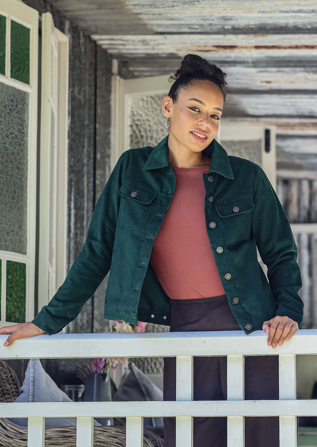 Woman wearing a deep blue-green jacket standing on a porch