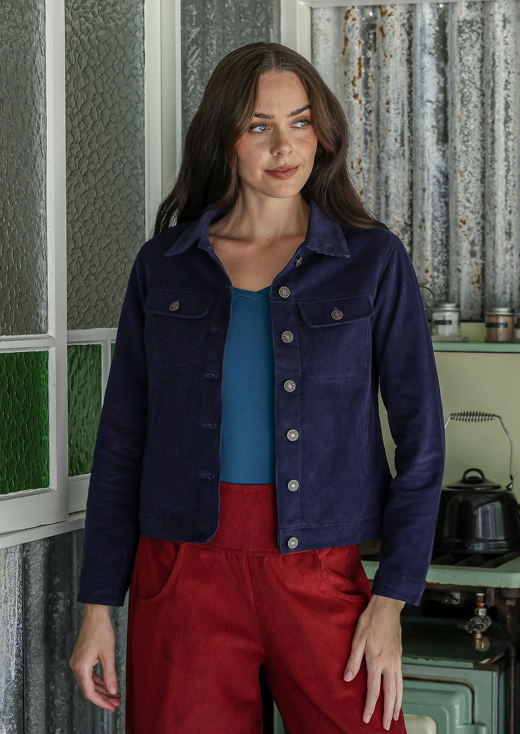 Woman wearing a deep, rich, and slightly muted navy blue jacket standing in a kitchen