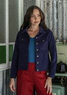 Woman wearing a deep, rich, and slightly muted navy blue jacket standing in a kitchen