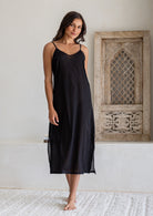 Woman wears black cotton voile maxi slip with V-neckline, spaghetti straps and side splits