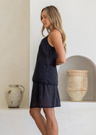 Side view of model in lightweight cotton slip skirt in black with matching cami, both with picot trim 