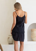 Back view of model in lightweight cotton slip skirt in black with matching cami, both with picot trim 