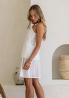 Side view of model in lightweight cotton slip skirt in white with matching cami, both with picot trim 