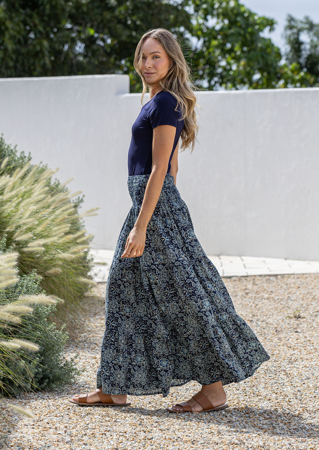 Model standing sideways wearing a three tiered, cotton maxi skirt with plain basic top