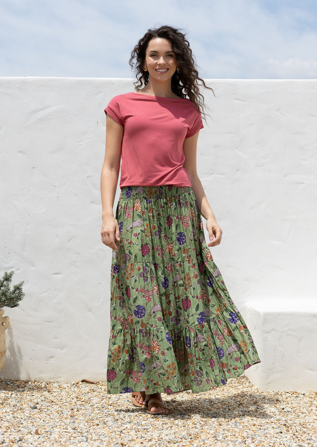 Woman wearing a cotton maxi skirt with wide elastic shirred waistband, in moss green based floral pattern.