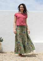 Woman wearing a cotton maxi skirt with wide elastic shirred waistband, in moss green based floral pattern.